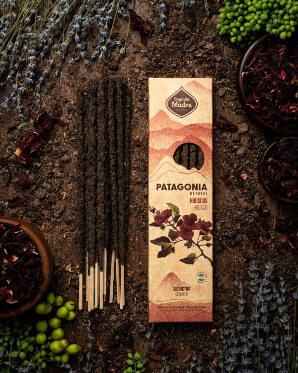 Una foto del Sahumerio Patagonia Seductor, con sus varillas oscuras con flores de hibisco. Rodeado de flores de lavanda y plantas verdes